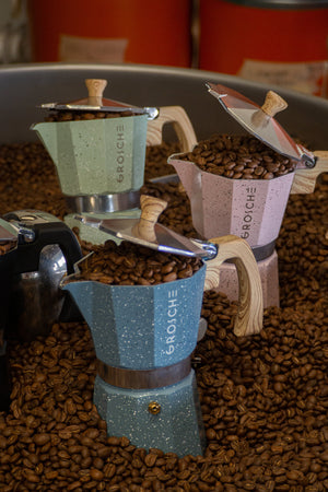 Cafetières italiennes de la marque Grosche en vente chez Arlo's Coffee. Les cafetières sont dans le refroidisseur du torréfacteur et sont parmi les kilos de grains de café qui viennent d'être torréfiés