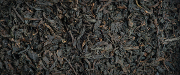Lapsang Souchong Bio / L'autre thé / Thé noir fumé / Le terme Lapsang Souchong désigne un thé noir fumé après récolte sur un feu de bois de pin, afin de lui donner une saveur boisée et fumée bien particulière. On appelle également cette catégorie « thés fumés » ou « Zheng Shan Xiao Zhong ».  Ce thé bio Lapsang Souchong est un thé fumé de Chine à la racine de pin. Clair à la tasse, très aromatique, il accompagne délicatement les plats salés ou épicés. En vente chez Arlo’s Coffee, artisan torréfacteur 